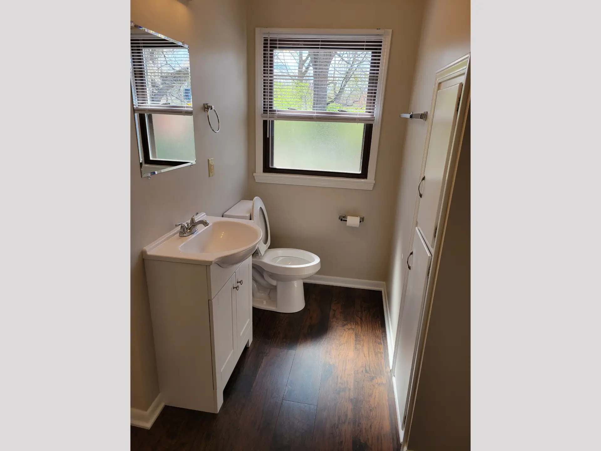 Compact bathroom with white fixtures and a window overlooking greenery.