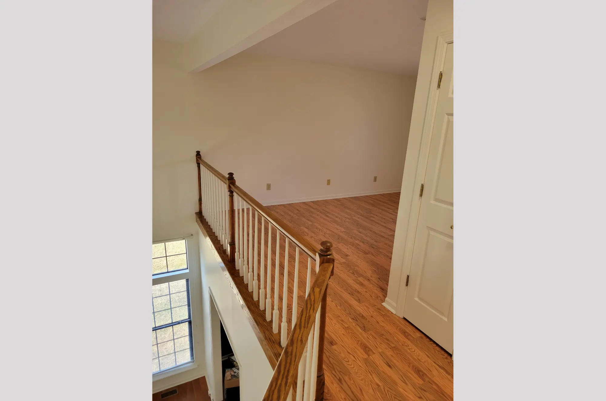 Empty room with wooden floor and staircase railing.