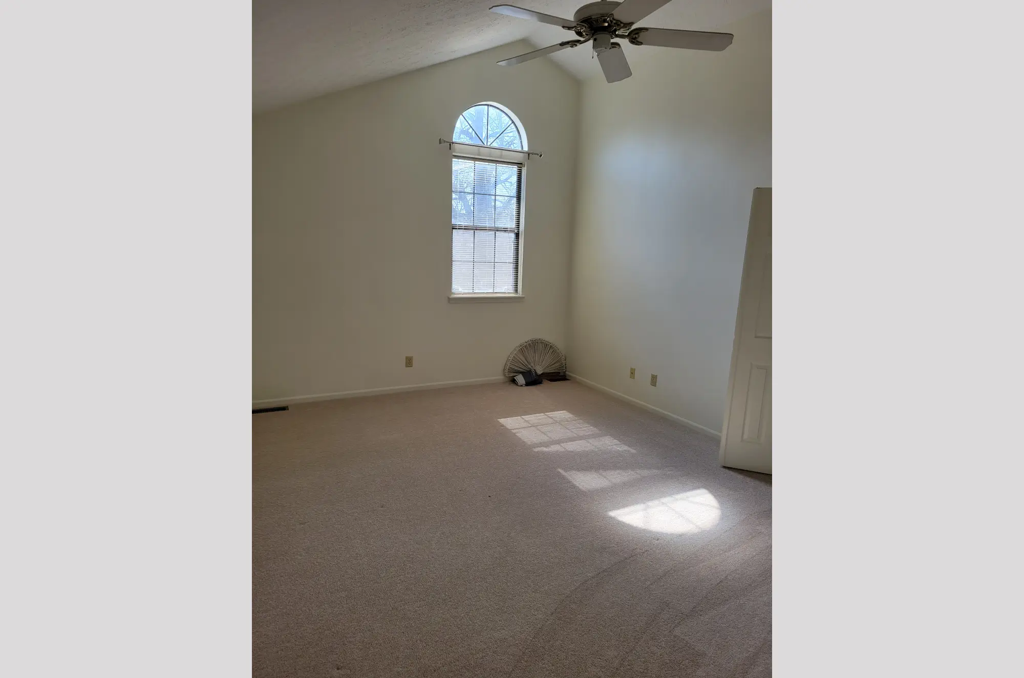Empty room with beige carpet and a window with an arched top.