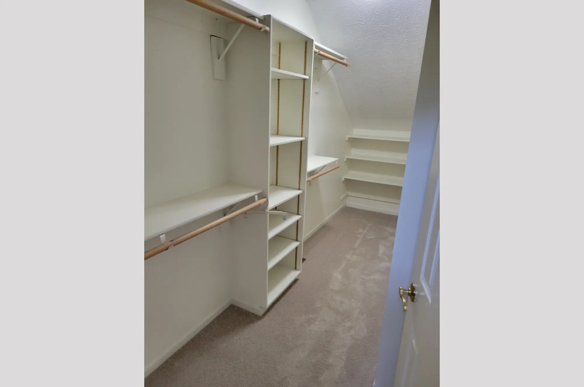 Spacious walk-in closet with built-in shelves and hanging rods.