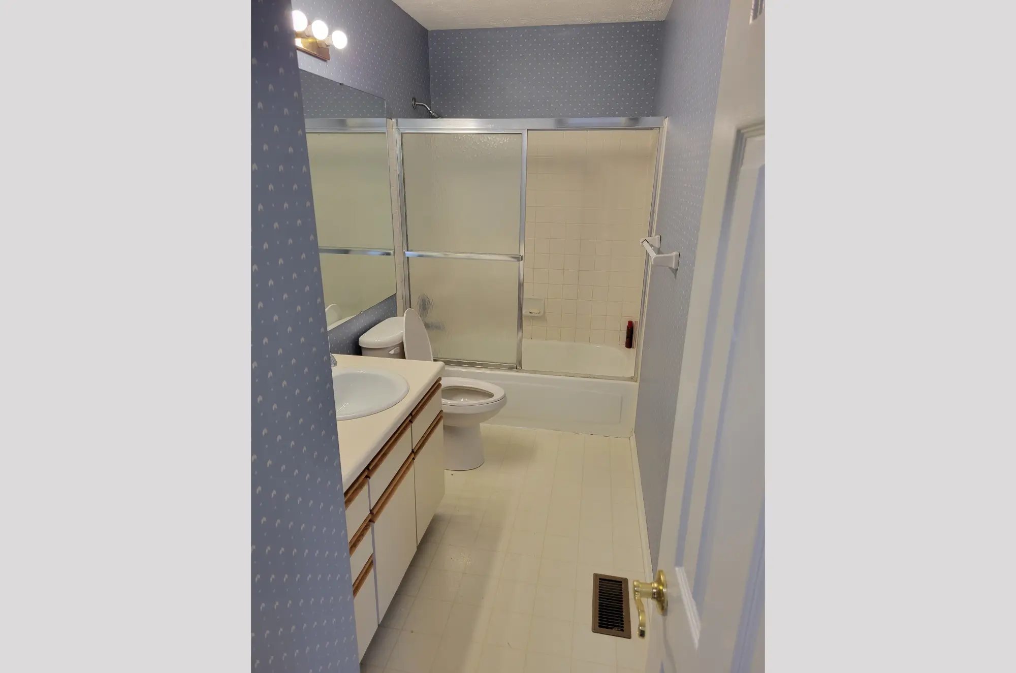 Modern bathroom with white tiles and glass shower enclosure.
