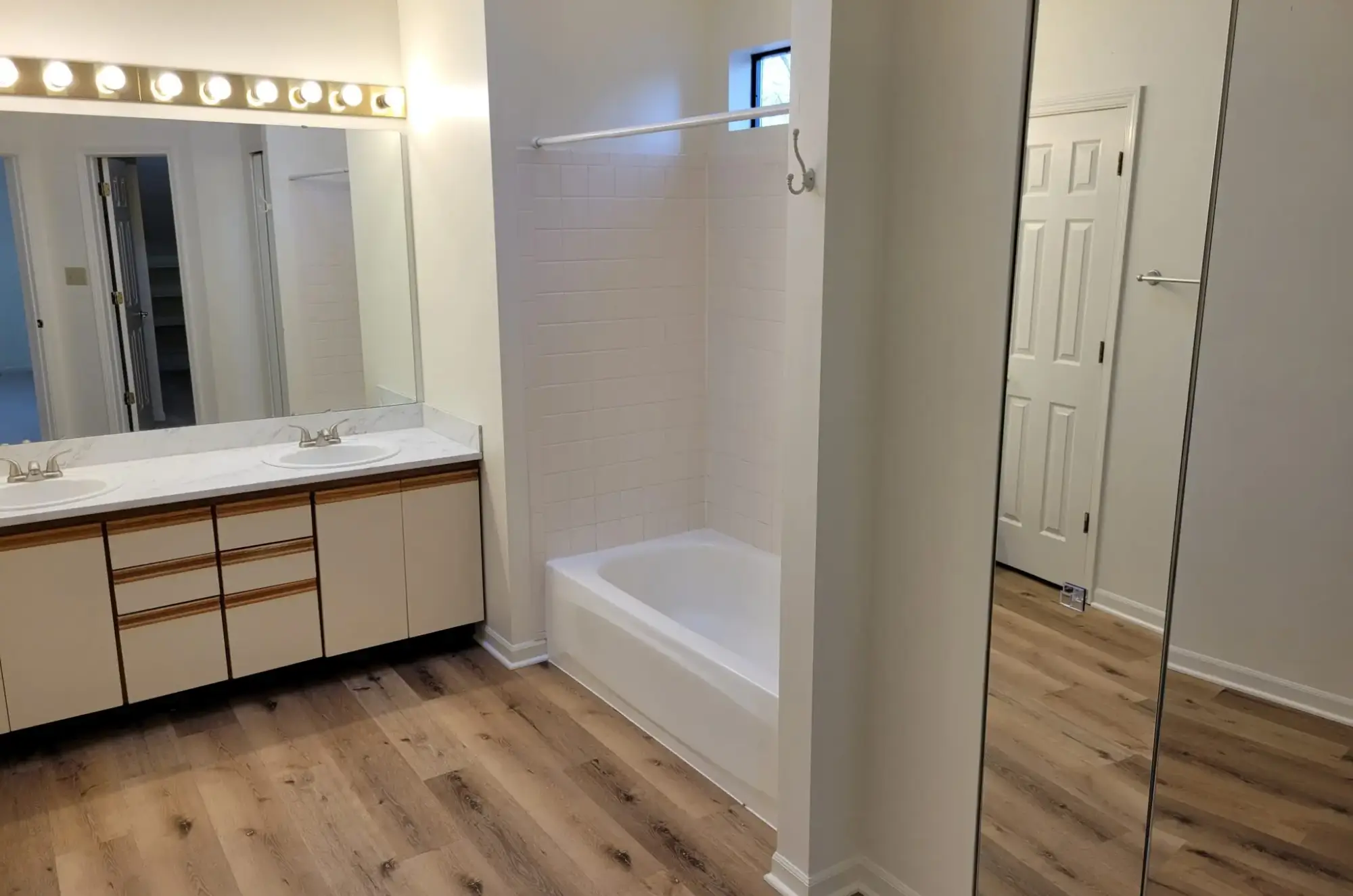 Minimalist bathroom with bathtub and wooden floor.