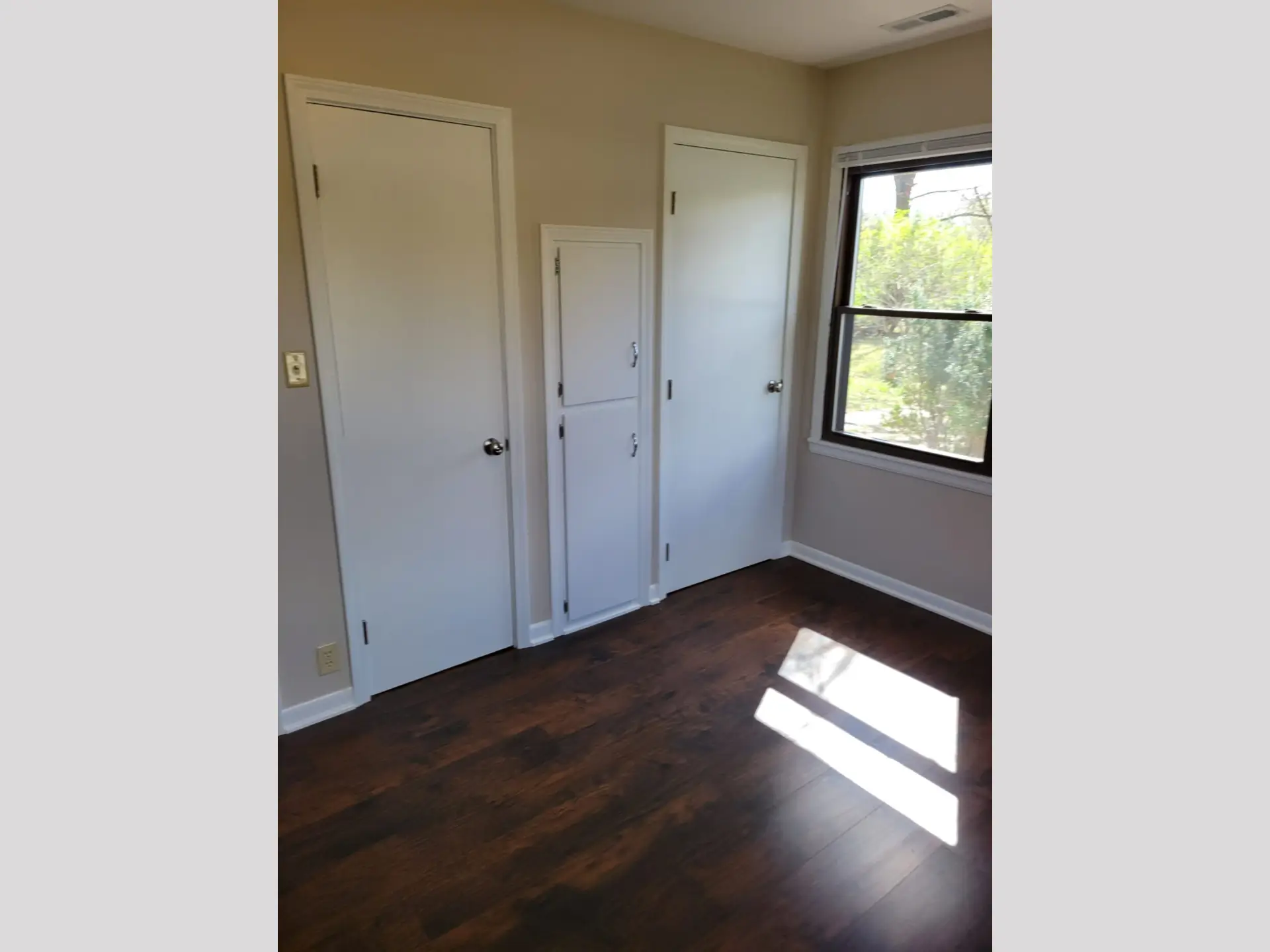 Empty room with two white doors and a window.